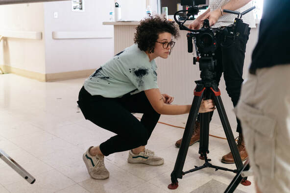 Biracial female in black overalls working cameral on film set |  Creativity Coaching for Writers, Singers, Performers, Musicians, Artists and Creative People- Online Creativity Coaching With Cindy Cisneros in Maryland, Virginia, Georgia, Maine, Utah, New York, California and throughout the USA