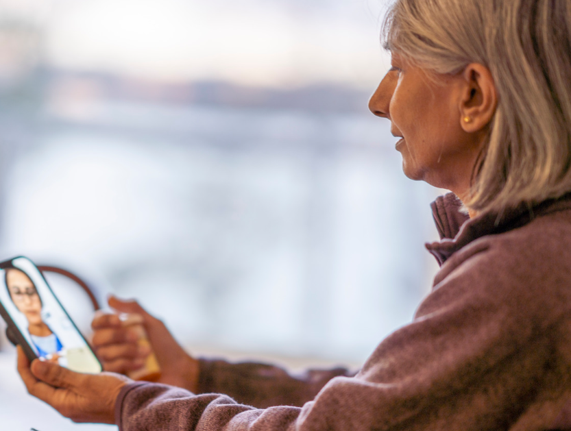 Therapy for Artists, Therapy for Artists in Maryland and Virginia, Online Therapy for Artists, Counseling for Artists and Creatives in Maryland and Virginia |  Adult 50+ female seated in profile engaged in Telehealth appointment on cellphone