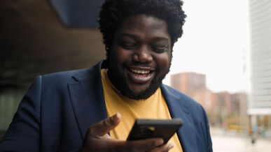 Picture of a black man looking at his phone and smiling. Creative people can thrive on stress and pressure in a way that makes them succeed. Counseling for creative people in Maryland or Virginia can help you find your creative balance around anxiety and stress here.