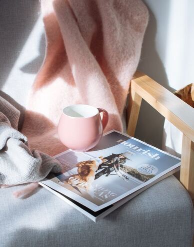 magazine, pink mug, pink blanket on gray chair |  concierge counseling and out of network counseling at creatively llc 