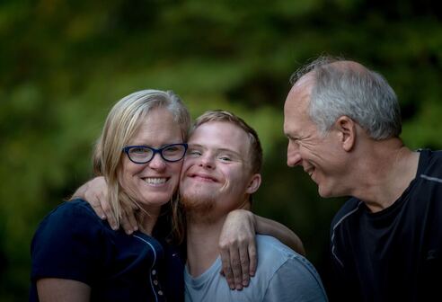family embracing, smiling, with child with downs syndrome in center |  concierge counseling for families in Maryland 