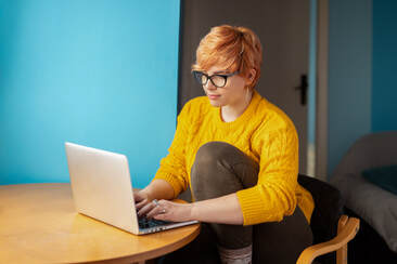 Young woman in yellow sweater at table with laptop writing | Online Creativity Coaching is available in NY, MD, VA, ME, UT, GA, CA and beyond with Creativity Coach Cindy Cisneros: Creativity Coaching for Writers
