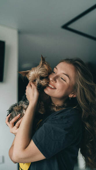 Female holding small dog, smiling| Authenticity, Self Esteem and Creativity in Therapy