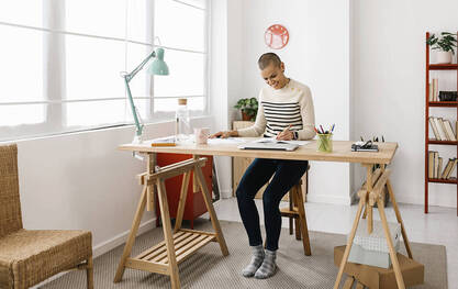 Picture of a working artist at her desk. Get creativity coaching for more positive mental health and creativity in Richmond, VA and Baltimore, MD here. Creativity Coaches in Germany, United States, Canada, UK and beyond can help!
