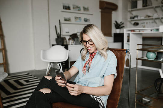 Adult female seated in living room using cellphone | Virtual Creativity Coaching Packages at Creatively, LLC